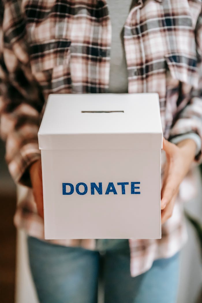 Close-up of a person holding a donate box, encouraging charity and support.